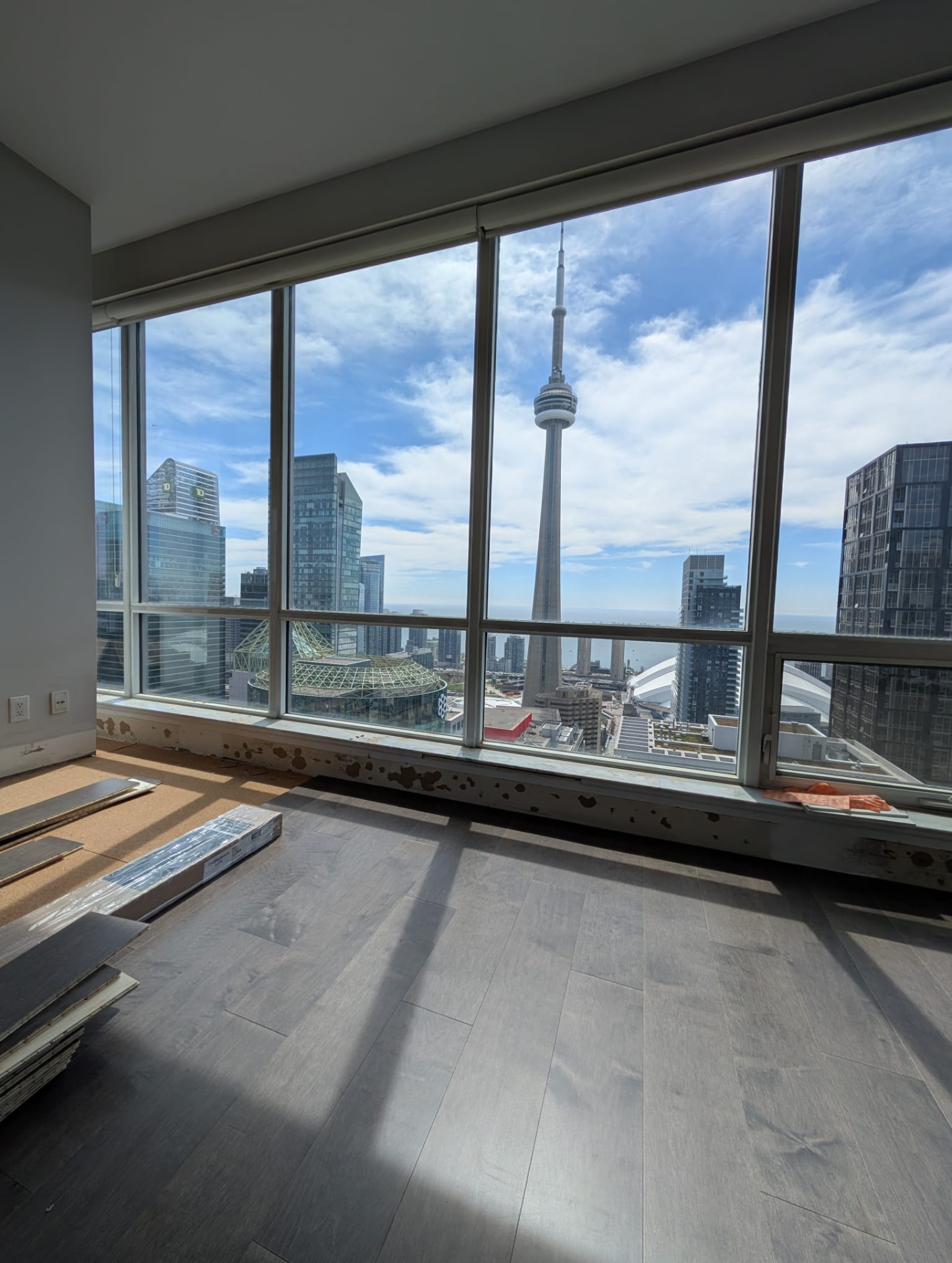 Dark plank flooring being installed with the Toronto skyline visible